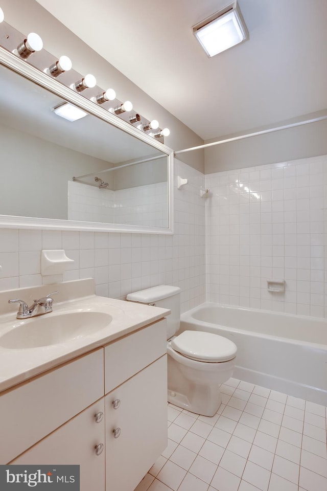 bathroom with toilet,  shower combination, tile patterned flooring, vanity, and tile walls