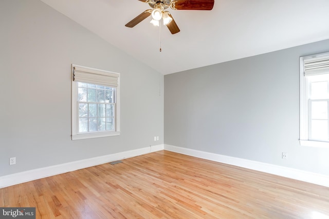 empty room featuring light wood-style floors, visible vents, vaulted ceiling, and baseboards