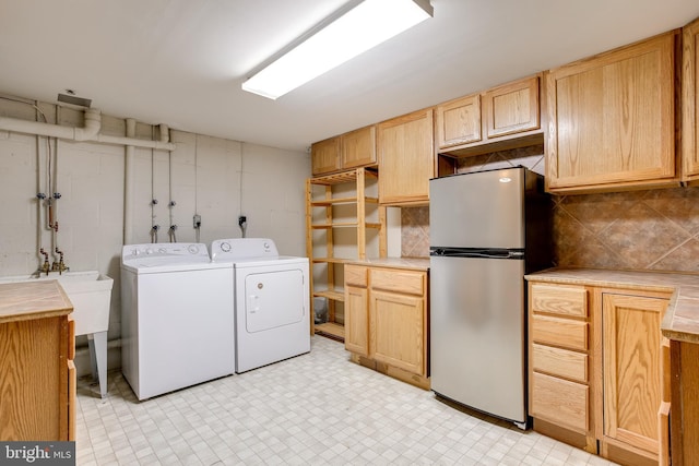 laundry area with concrete block wall, laundry area, light floors, and independent washer and dryer