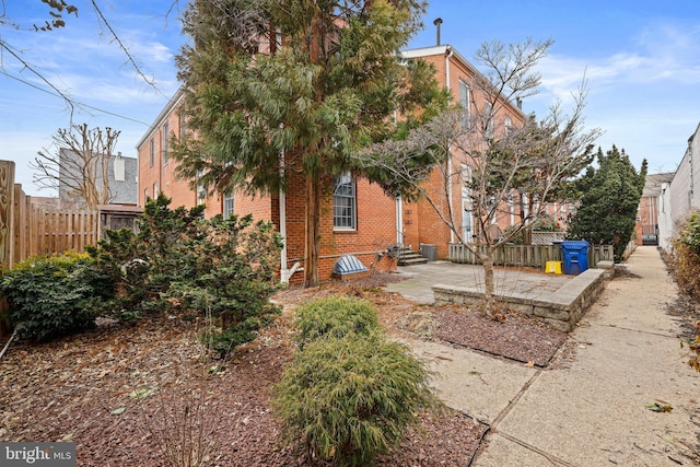 back of house featuring a patio, brick siding, and fence