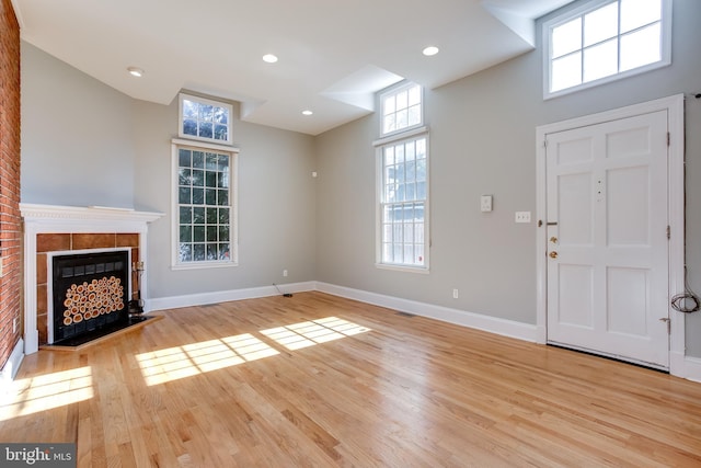 unfurnished living room with light wood-style flooring, a fireplace, baseboards, and recessed lighting