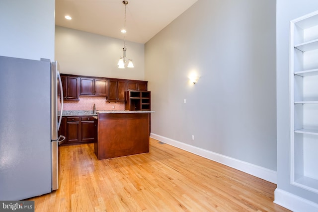 kitchen featuring a chandelier, hanging light fixtures, light countertops, freestanding refrigerator, and a center island