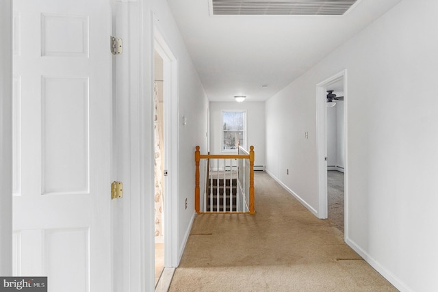 corridor with light colored carpet, visible vents, a baseboard heating unit, an upstairs landing, and baseboards