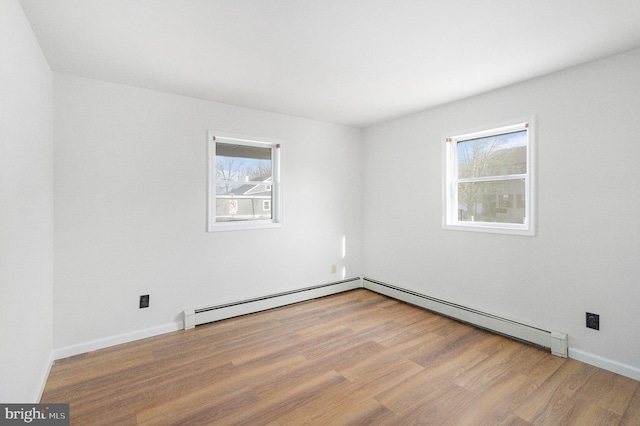 empty room with baseboards, light wood-style floors, a baseboard radiator, and a healthy amount of sunlight