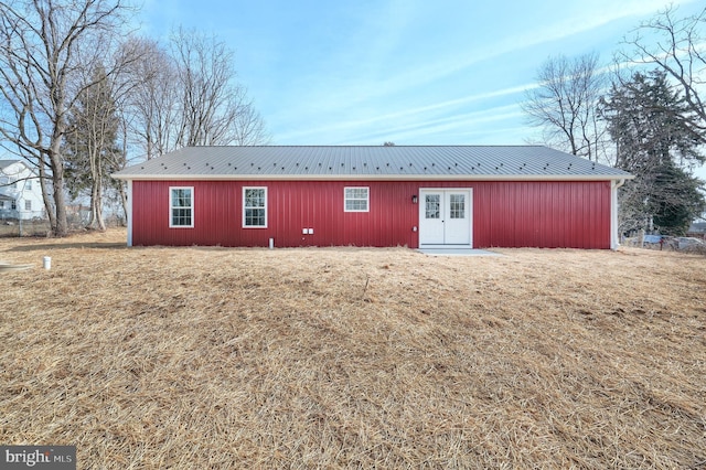 back of property featuring metal roof and a yard