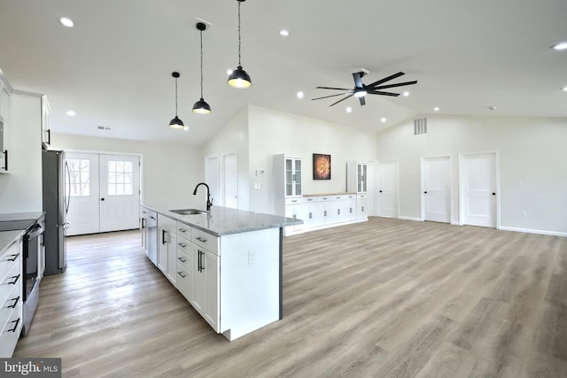 kitchen with a kitchen island with sink, white cabinetry, appliances with stainless steel finishes, and light stone counters