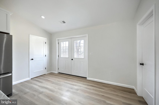 foyer entrance with light wood finished floors, baseboards, lofted ceiling, french doors, and recessed lighting