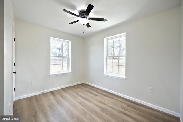 spare room featuring a healthy amount of sunlight, light wood-style flooring, baseboards, and a ceiling fan