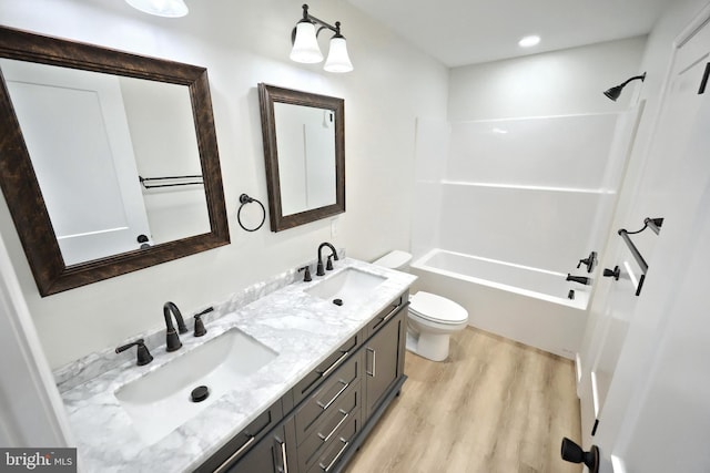 bathroom with double vanity, a sink, toilet, and wood finished floors