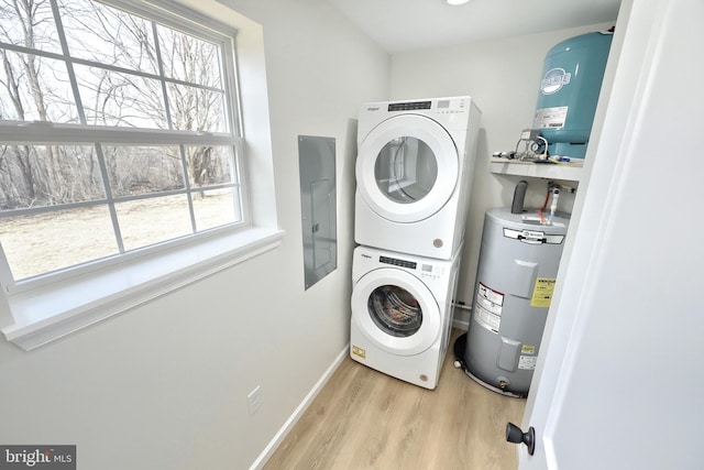 laundry room with stacked washer and clothes dryer, water heater, light wood-type flooring, laundry area, and electric panel