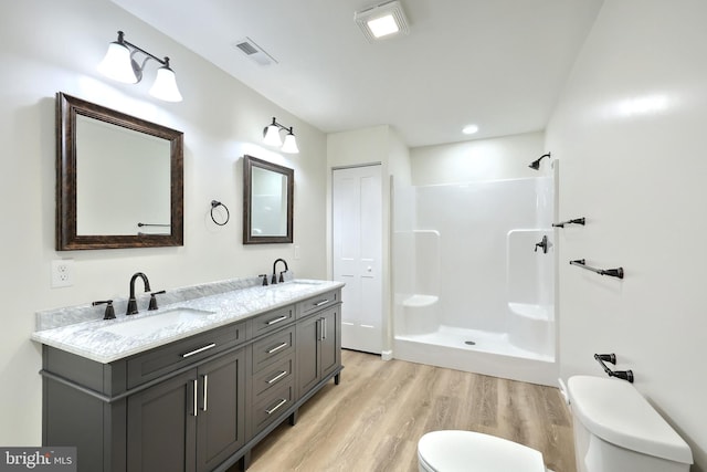 full bath with toilet, visible vents, a sink, and wood finished floors