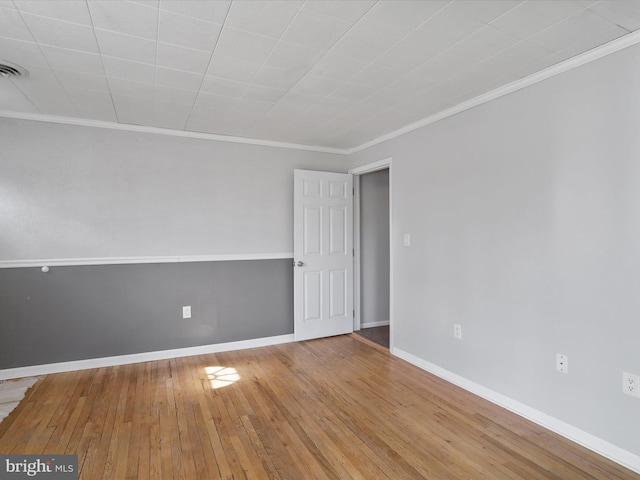 unfurnished room with ornamental molding, wood finished floors, visible vents, and baseboards