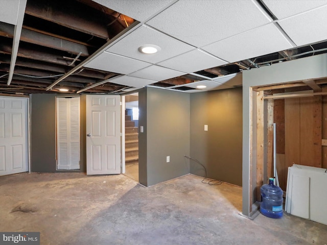 finished basement with a paneled ceiling and stairway