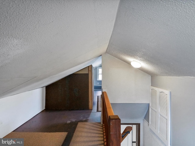 bonus room with lofted ceiling and a textured ceiling