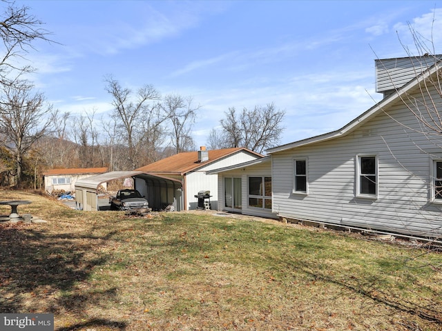 rear view of property featuring a carport and a yard