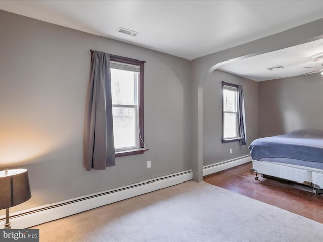 bedroom featuring a baseboard radiator, multiple windows, and visible vents