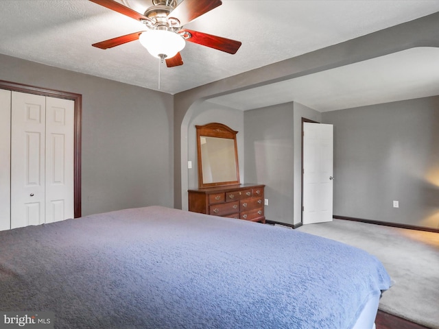 bedroom featuring a textured ceiling, carpet floors, a ceiling fan, baseboards, and a closet