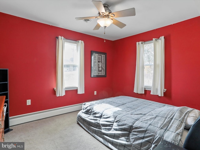 carpeted bedroom with a baseboard heating unit, multiple windows, and ceiling fan