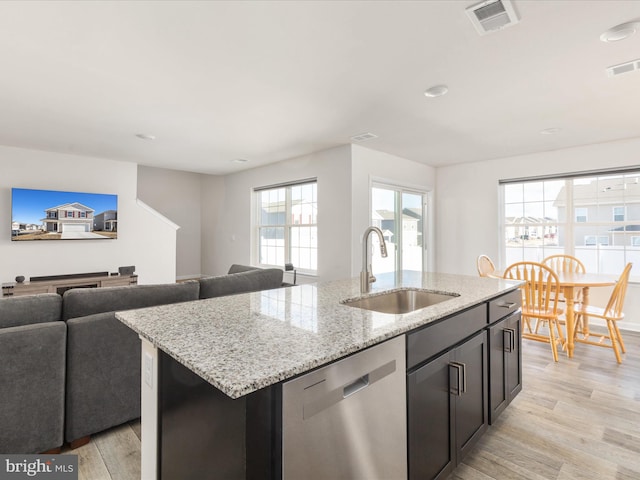 kitchen featuring a sink, visible vents, open floor plan, stainless steel dishwasher, and a center island with sink