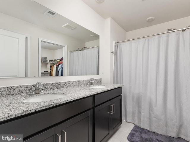 bathroom featuring visible vents, a sink, a spacious closet, and double vanity