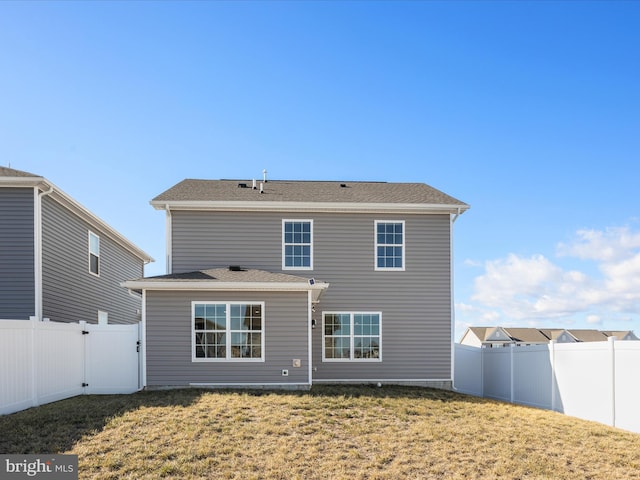 rear view of house with a yard and a fenced backyard