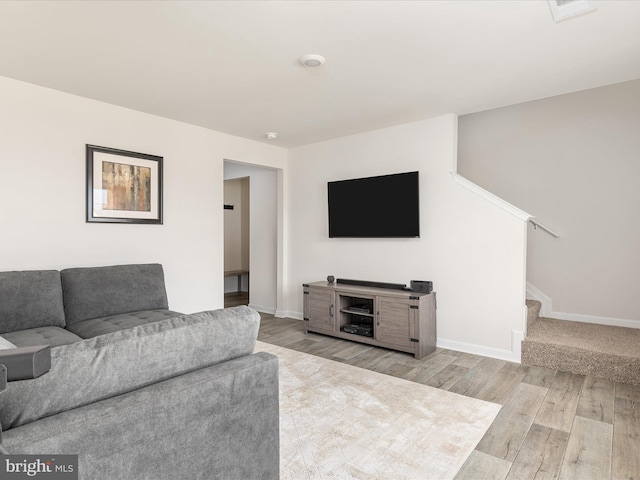 living area with stairs, light wood-style flooring, and baseboards