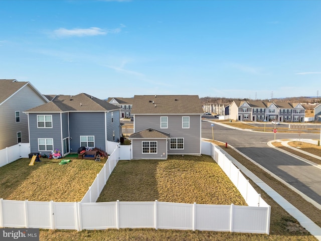 view of front of property with a front lawn, a fenced backyard, and a residential view