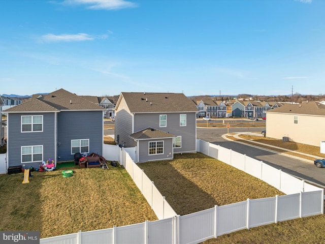 rear view of property with a residential view, a fenced backyard, and a lawn