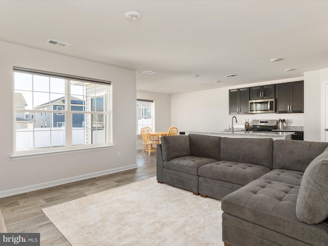 living room featuring baseboards, visible vents, and light wood-style floors