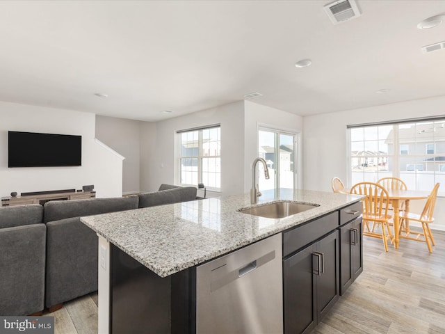 kitchen featuring a kitchen island with sink, a sink, visible vents, open floor plan, and dishwasher