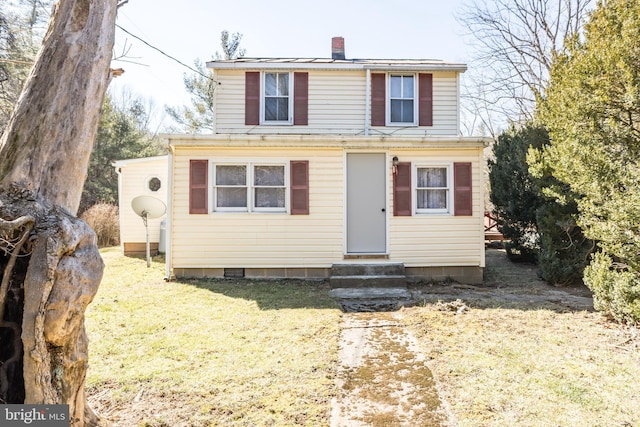 view of front of home with entry steps, a chimney, and a front yard