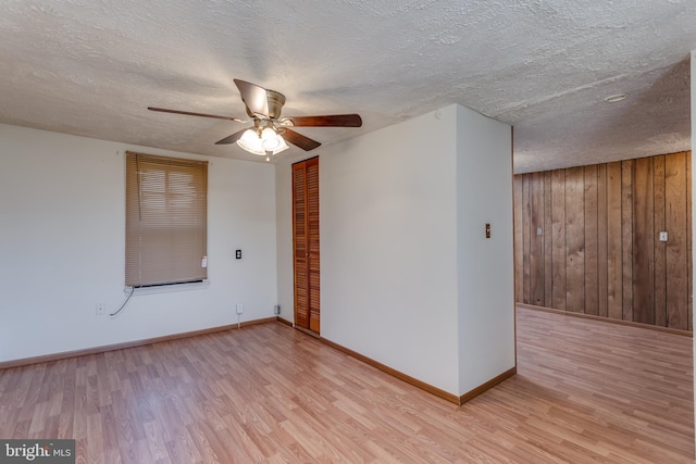 unfurnished room featuring light wood-type flooring, baseboards, and a textured ceiling