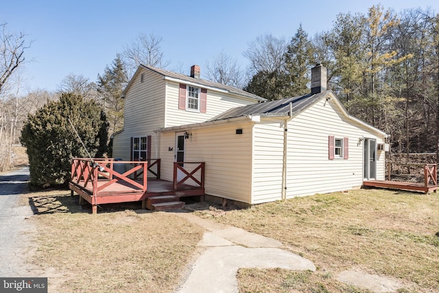 exterior space featuring a deck, metal roof, a front lawn, and a chimney