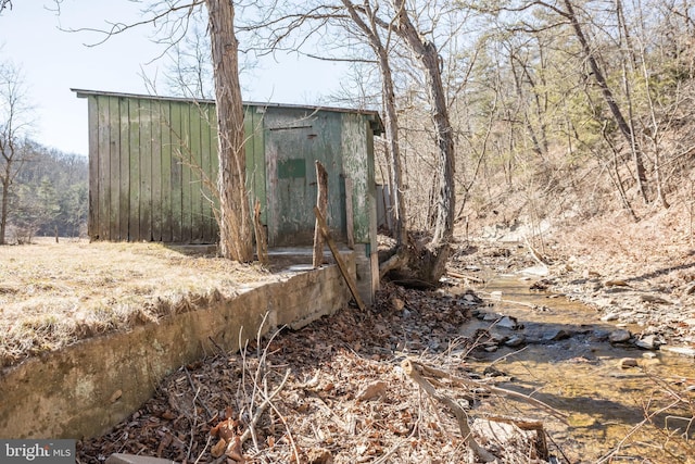 view of outdoor structure with a forest view and an outbuilding