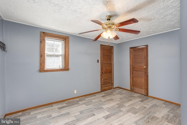 spare room featuring a textured ceiling, ceiling fan, baseboards, and light wood-style floors