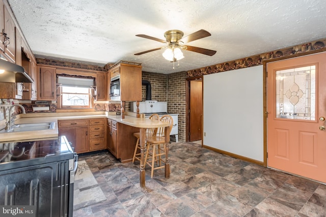 kitchen featuring light countertops, a sink, a textured ceiling, built in microwave, and a peninsula