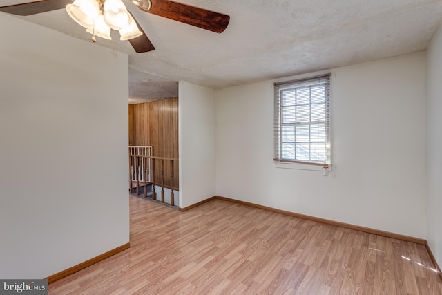 spare room with a textured ceiling, baseboards, and wood finished floors