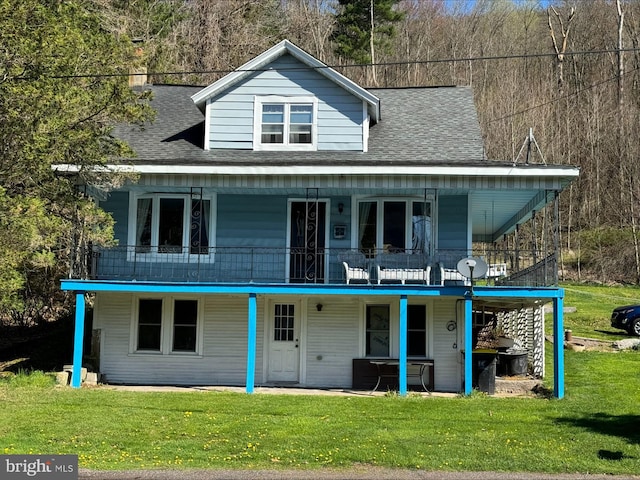 rear view of property with a shingled roof and a lawn