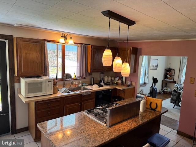 kitchen with light stone counters, hanging light fixtures, white microwave, a sink, and dishwasher