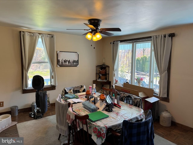 dining space with ceiling fan and baseboards