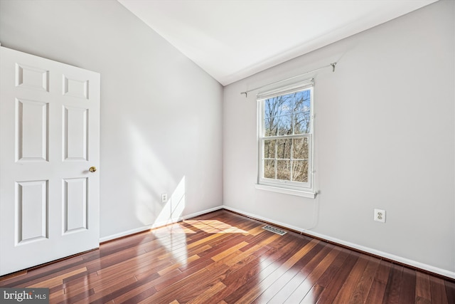 spare room featuring lofted ceiling, hardwood / wood-style flooring, baseboards, and visible vents