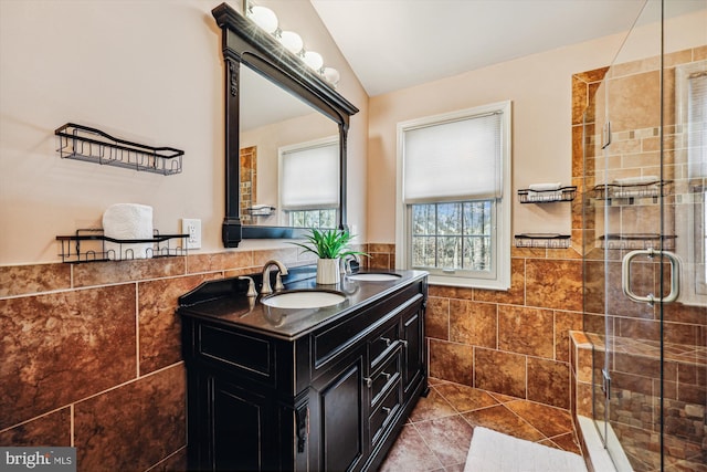 bathroom featuring a stall shower, wainscoting, a sink, and tile walls