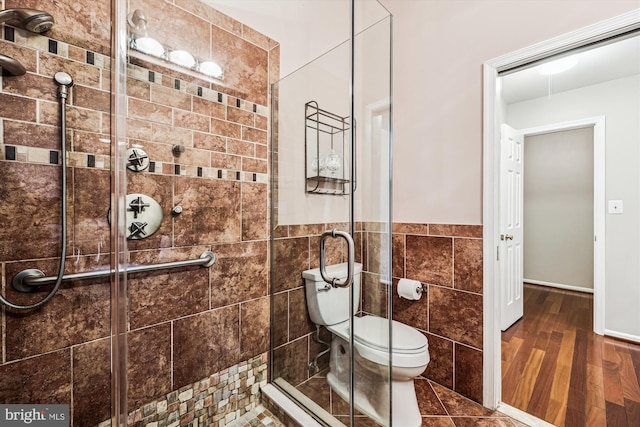 bathroom featuring toilet, a stall shower, tile walls, and wood finished floors