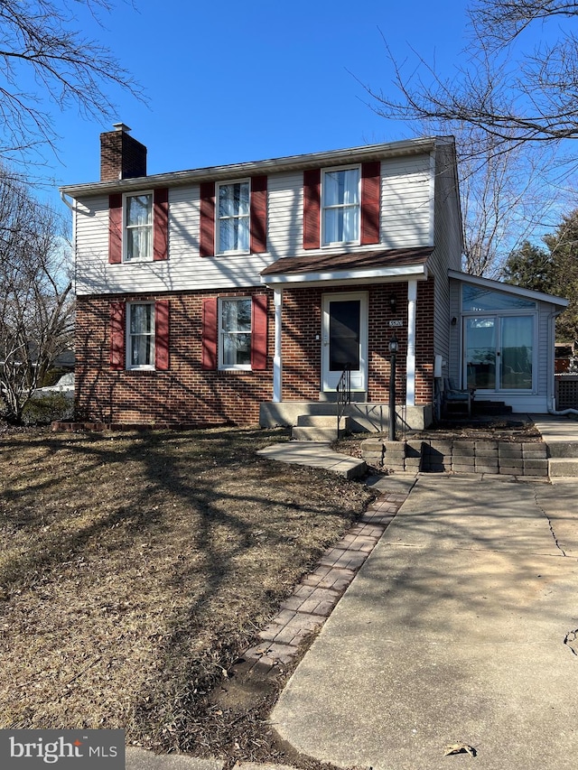 traditional-style house featuring brick siding and a chimney