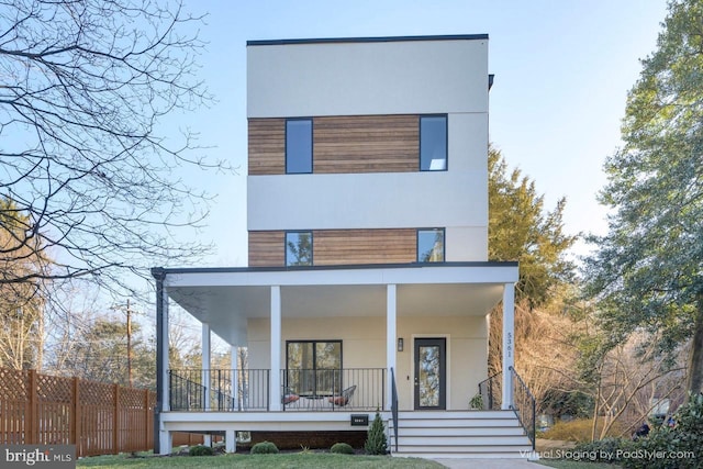 view of front of property featuring covered porch, fence, and stucco siding