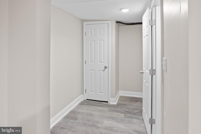 hall with light wood-style flooring and baseboards