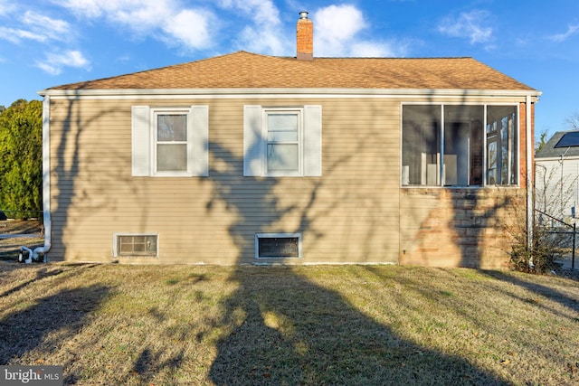 view of property exterior featuring a sunroom, a lawn, and a chimney