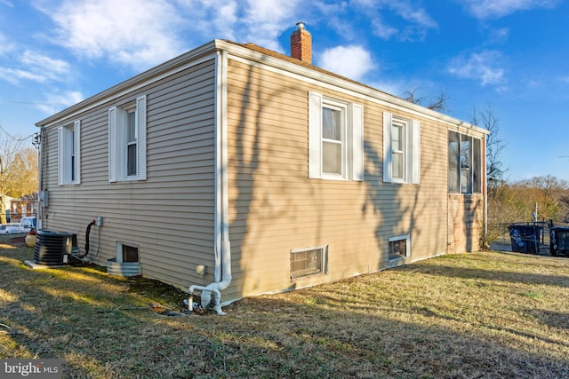 view of side of property featuring a lawn, a chimney, and central air condition unit