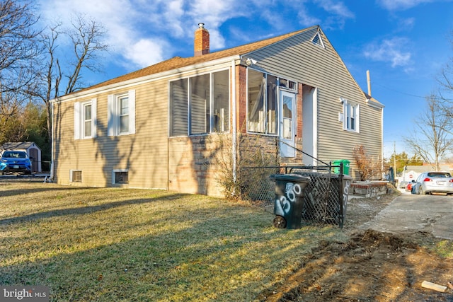 view of property exterior with a sunroom, a lawn, and a chimney