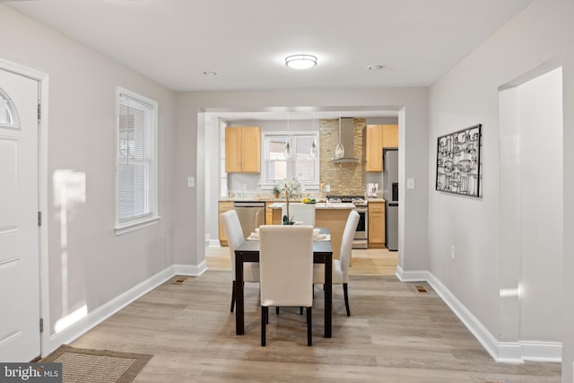 dining space featuring light wood-style flooring and baseboards